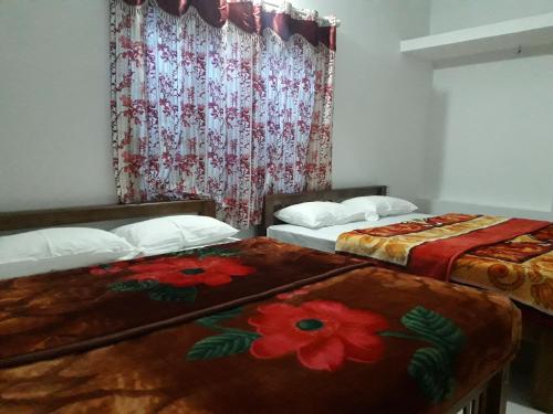 Cette chambre comprend 2 lits et une fenêtre fleurie. dans l'établissement Munnar Brindavan Cottage, à Munnar