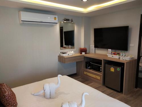 a hotel room with a tv and a couch with a table at Hotel De Sripoom in Chiang Mai