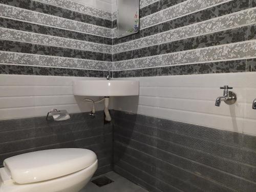 a bathroom with a toilet and black and white tiles at Munnar Brindavan Cottage in Munnar