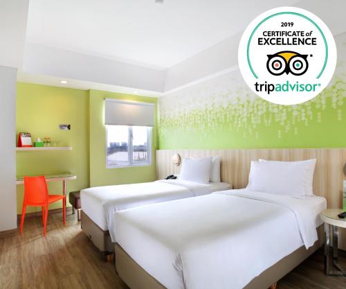 two beds in a room with a green wall at Zest Sukajadi Bandung by Swiss-Belhotel International in Bandung
