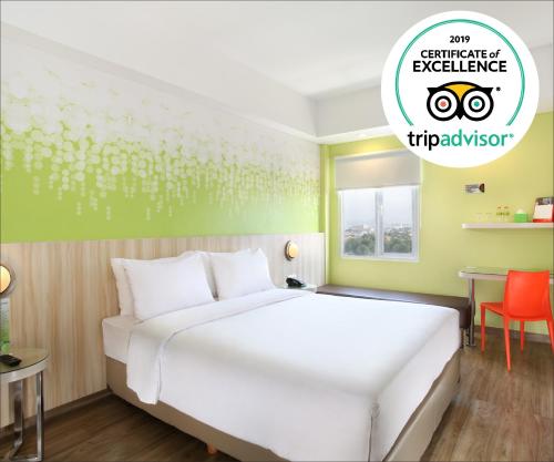 a bedroom with a white bed and a green wall at Zest Sukajadi Bandung by Swiss-Belhotel International in Bandung