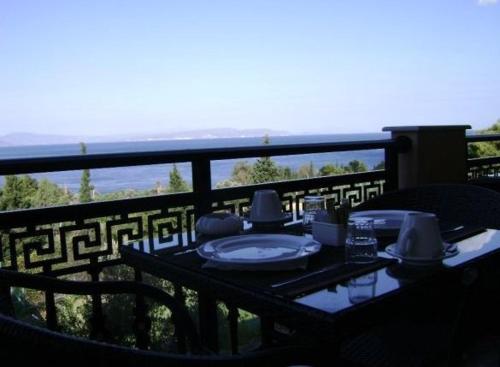 a table on a balcony with a view of the ocean at Pantheon Hotel & Suites in Nerotriviá