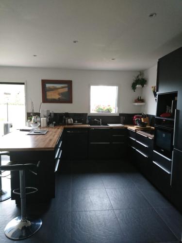 a kitchen with black cabinets and a wooden counter top at TY SAM BELLE MAISON MODERNE 8 à 10 personnes - PROCHE plages et commerces in Trébeurden
