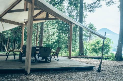 Retreat Camp Mahoroba في فوجيكاواجوتشيكو: سطح خشبي مع طاولة وكراسي في الغابة