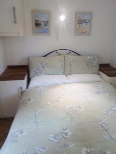 a bed with a white bedspread with flowers on it at new pottery in Penzance