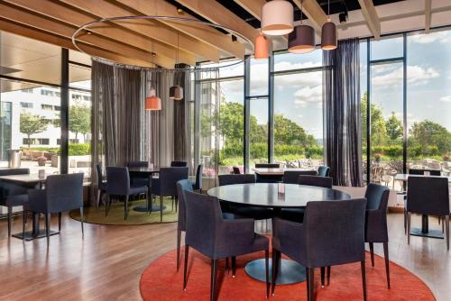 a dining room with tables and chairs and large windows at Quality Hotel Expo in Fornebu