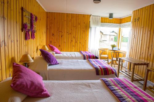 um quarto de hotel com duas camas com almofadas roxas em Hotel del Paine em Torres del Paine