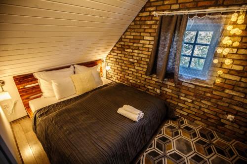 ein Schlafzimmer mit einem großen Bett in einer Ziegelwand in der Unterkunft Borárium Vendégházak - Néró Ház in Pázmánd