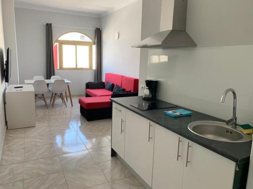 a kitchen with a sink and a red couch at TABLERO 303, FABULOSO apto 6 pax cerca de PLAYA INGLÉS in El Tablero