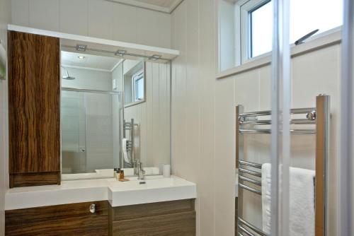 a bathroom with a sink and a mirror at Peppers Lodge, Strawberryfield Park in Cheddar