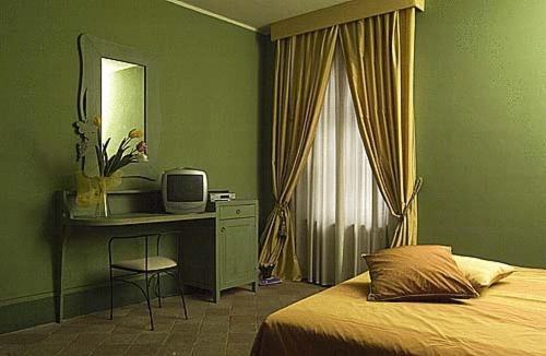 a bedroom with a bed and a desk with a television at Locanda Martelletti in Cocconato