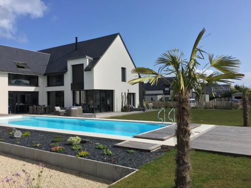 une maison avec une piscine et un palmier dans l'établissement Le Petit Lupin, à Saint-Coulomb