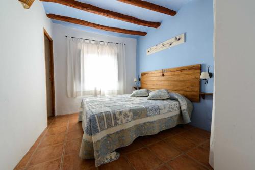 sypialnia z łóżkiem z niebieskimi ścianami i oknem w obiekcie Casa rural Lo Regolfo w mieście La Codoñera