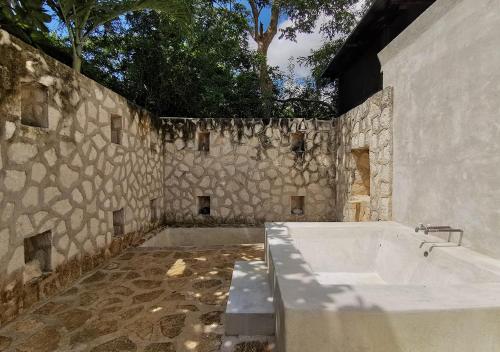 a bathroom with a stone wall and a bath tub at Coqui Coqui Papholchac Coba Residence & Spa in Cobá
