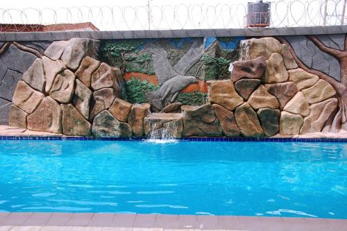 una piscina con una pared de roca y una cascada en MJ Grand Hotel, en East Legon