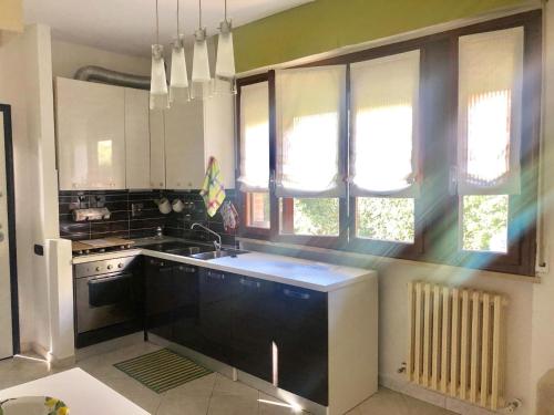 Casa del Sole - Sunshine Home في مارينا دي بيزا: مطبخ مع حوض وموقد ونوافذ