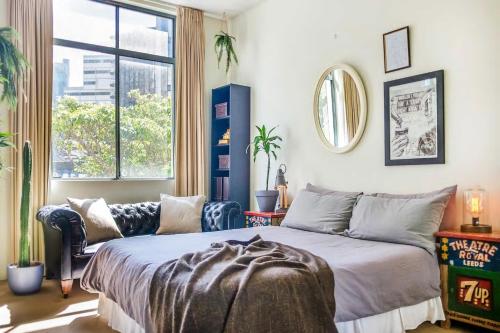 a bedroom with a bed and a couch and a window at Funky Surry Hills Warehouse by Sydney Dreams in Sydney