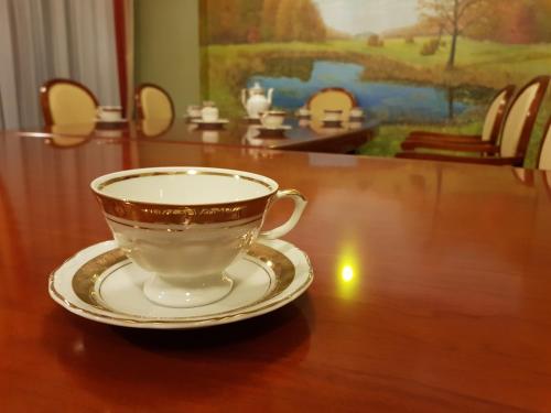 a cup and saucer on a wooden table at Rezydencja Pod Zegarem in Trzebinia