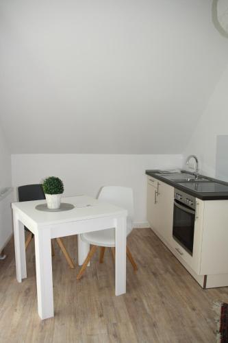eine Küche mit einem weißen Tisch, einem Tisch und einem Waschbecken in der Unterkunft Apartment Schoene Aussicht in Langwedel