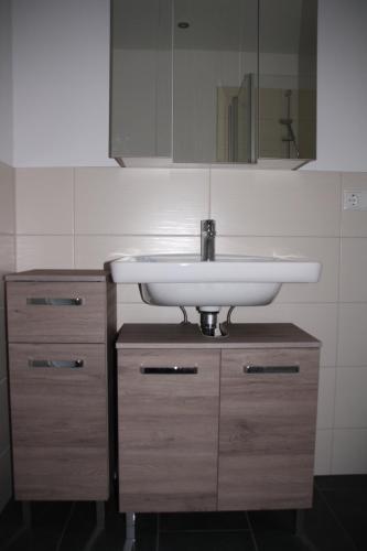 uma casa de banho com um lavatório branco e armários de madeira em Apartment Schoene Aussicht em Langwedel