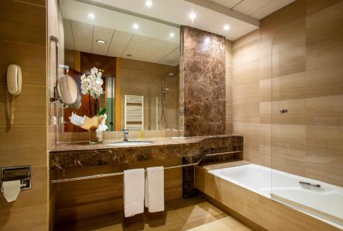ein Badezimmer mit einer Badewanne, einem Waschbecken und einem Spiegel in der Unterkunft Eurostars Acteón in Valencia
