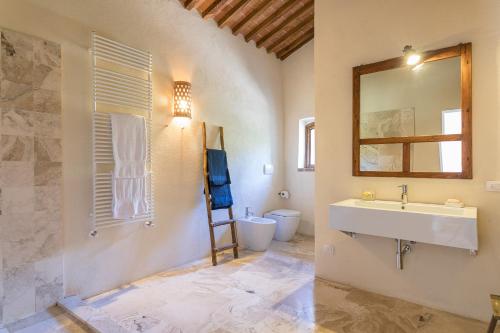 a bathroom with a sink and a toilet and a mirror at Villa Casenovole in Murlo