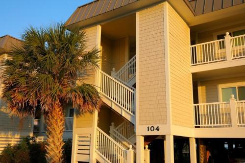 a building with a palm tree in front of it at Next 2 Paradise-203 in Holden Beach