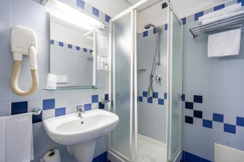 y baño azul y blanco con lavabo y ducha. en Europa Palace Hotel, en Messina