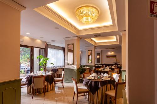 a restaurant with tables and chairs and a chandelier at Europa Palace Hotel in Messina