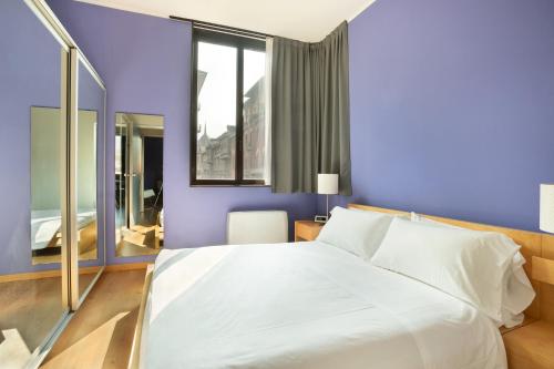 um quarto com uma grande cama branca e uma janela em Nizza26 Serviced Apartments em Turim
