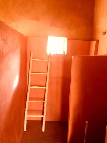 a ladder in the corner of a room with a window at Tigmi Hamid Découverte des traditions et de la culture berbère in Aït Ben Haddou