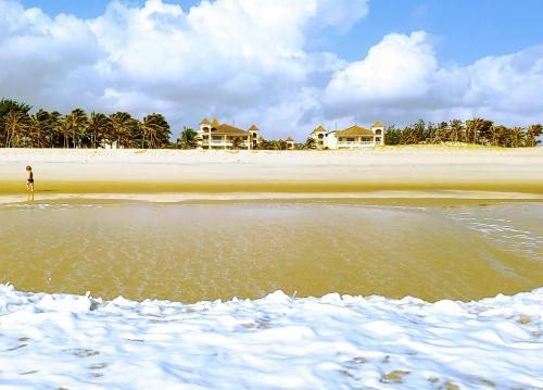 a person standing on a beach with houses in the background at Atlantic Palace Family inn in Aquiraz