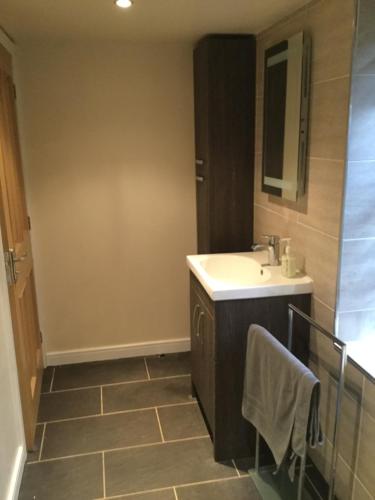 a bathroom with a sink and a mirror at Three Peaks View Cottage in Wigglesworth