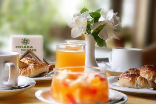 Una mesa con platos de comida y un jarrón con flores. en Hostería Posada del Sol, en Libertador General San Martín