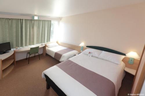a hotel room with two beds and a television at Ibis Alès Centre Ville in Alès