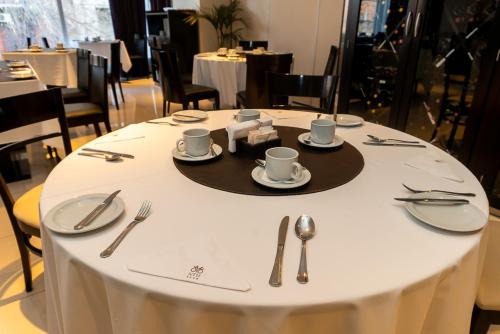 a table with plates and cups and utensils on it at Neuquén Tower Hotel in Neuquén