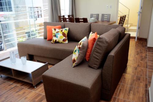 a living room with a brown couch with pillows at Hotel Apartamentos "Dominó" in Tarija