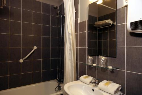 a bathroom with a sink and a tub and a toilet at Au Saint Roch - Hôtel et Jardin in Avignon