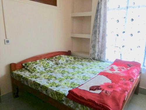 a small bedroom with a bed with a window at Pine Hill Home Stay in Shillong