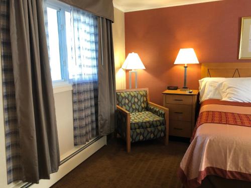 a hotel room with a bed and a chair and a window at Wilbraham Inn in Wilbraham