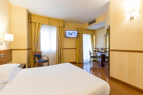 a hotel room with a white bed and a television at Best Western Hotel I Colli in Macerata