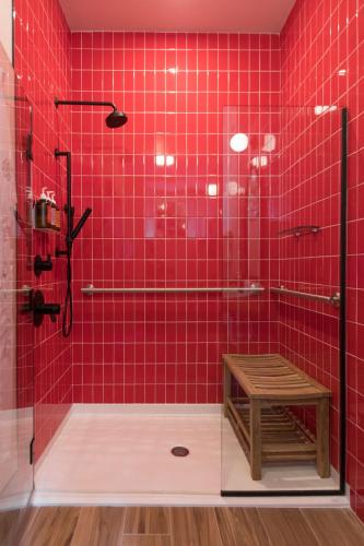 a red tiled bathroom with a shower with a wooden stool at The Russell in Nashville