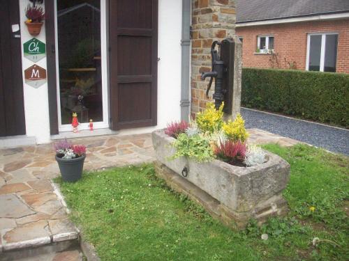 a stone planter in front of a house with flowers at Chez Lola in La Roche-en-Ardenne