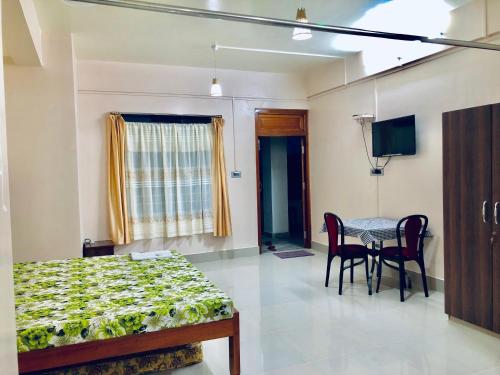 a bedroom with a bed and a table and a television at Pine Hill Home Stay in Shillong