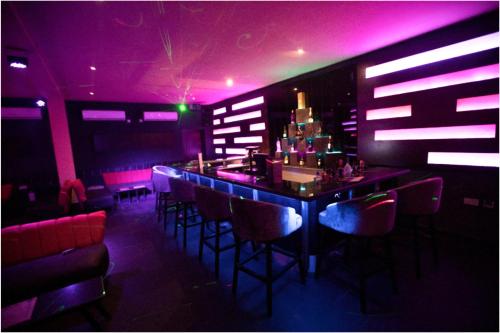 a bar in a nightclub with purple and pink lighting at Visa Karena Hotels in Port Harcourt