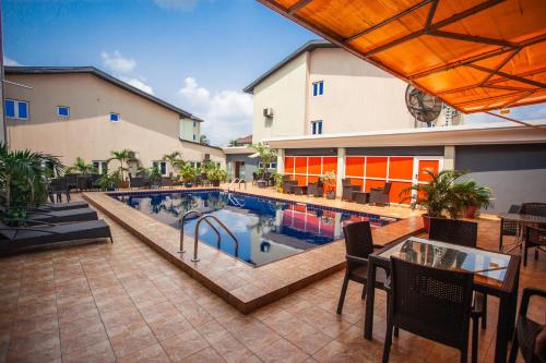 basen ze stołem i krzesłami obok budynku w obiekcie Visa Karena Hotels w mieście Port Harcourt