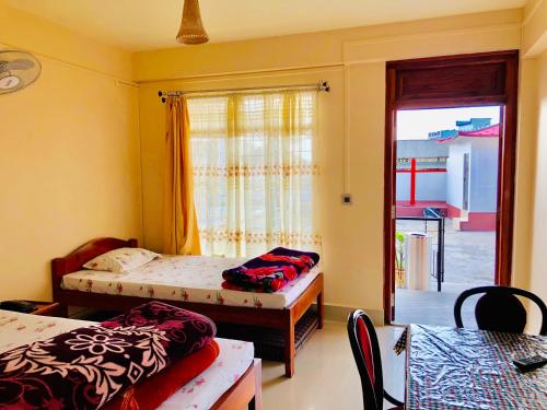 a bedroom with two beds and a door to a patio at Pine Hill Home Stay in Shillong