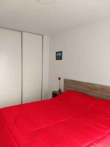 a bedroom with a red bed with a red blanket at MIKA in Puerto Madryn