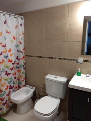 a bathroom with a toilet and a sink and a shower curtain at MIKA in Puerto Madryn