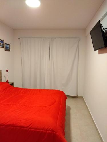 a bedroom with a red bed and a white curtain at MIKA in Puerto Madryn